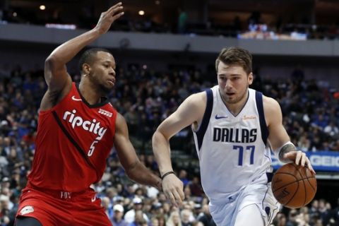 Portland Trail Blazers' Rodney Hood (5) defends as Dallas Mavericks forward Luka Doncic (77) drives to the basket for a shot in the first half of an NBA basketball game in Dallas, Sunday, Feb. 10, 2019. (AP Photo/Tony Gutierrez)