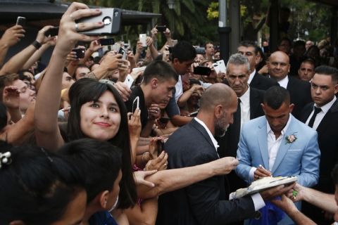 In this Thursday, Dec. 22, 2016 photo, a fan takes a selfie as soccer idol Carlos Tevez signs autographs outside the church where he married Vanesa Mansilla in Buenos Aires, Argentina. The Boca Juniors player is negotiating his transfer to China's Shanghai Shenhua team. (AP Photo/Luciano Matteazzi)