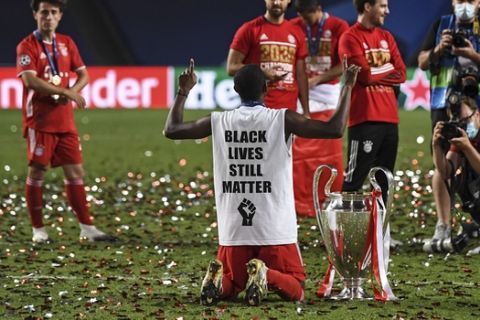 Bayern's David Alaba knees with a Black Lives Matter shirt beside the trophy on the pitch after the Champions League final soccer match between Paris Saint-Germain and Bayern Munich at the Luz stadium in Lisbon, Portugal, Sunday, Aug. 23, 2020. (David Ramos/Pool via AP)