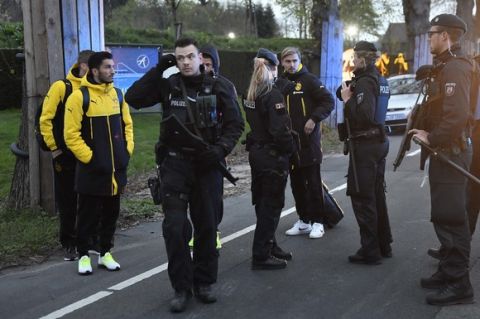 Dortmund's Marcel Schmelzer talks to police officers outside the team bus after it was damaged in an explosion before the Champions League quarterfinal soccer match between Borussia Dortmund and AS Monaco in Dortmund, western Germany, Tuesday, April 11, 2017.  (AP Photo/Martin Meissner)