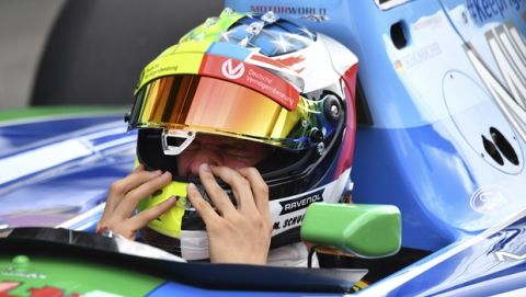Mick Schumacher, son of seven-time F1 world champion Michael Schumacher, adjusts his helmet prior to driving an exhibition lap ahead of the Belgian Formula One Grand Prix in Spa-Francorchamps, Belgium, Sunday, Aug. 27, 2017. Mick Schumacher will mark the 25th anniversary of his father's maiden Grand Prix victory by demonstrating one of his championship-winning cars ahead of Sunday's race in Belgium. (AP Photo/Geert Vanden Wijngaert)