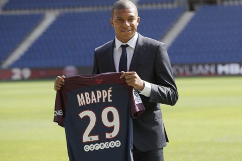 French soccer player Kylian Mbappe poses with his team shirt following a press conference in Paris, Wednesday, Sept. 6, 2017. Mbappe is a young man in a big hurry and wants to "win everything" with his new club Paris Saint-Germain. (AP Photo/Christophe Ena)