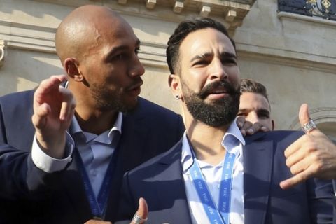 France defender Djibril Sidibe, right, holds the World Cup trophy as midfielder Steven N'Zonzi, left, speaks with defender Adil Rami during an official reception at the Elysee Presidential Palace in Paris, Monday, July 16, 2018. France is readying to welcome home the national soccer team for a parade down the Champs-Elysees, where tens of thousands thronged after the team's 4-2 victory over Croatia Sunday. (Ludovic Marin/Pool Photo via AP)