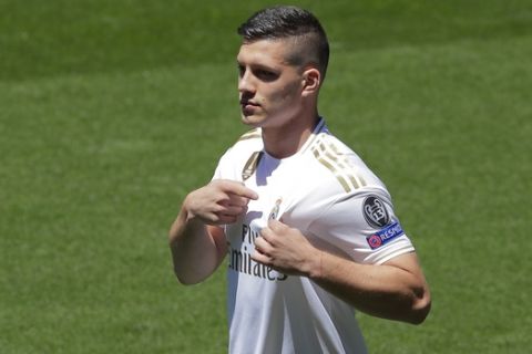 Serbia forward Luka Jovic points to the club emblem on his shirt during his official presentation after signing for Real Madrid at the Santiago Bernabeu stadium in Madrid, Spain, Wednesday, June 12, 2019. The 21-year-old Jovic, who scored 17 goals in 32 Bundesliga games for Eintracht Frankfurt last season, agreed to a six-year deal with Madrid. (AP Photo/Manu Fernandez)