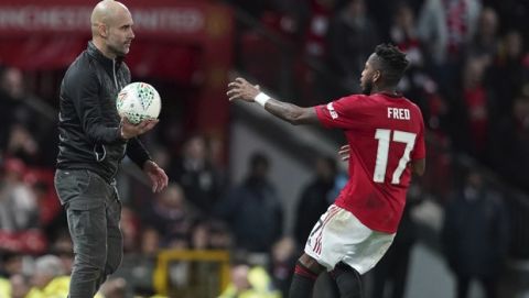 Manchester City's manager Pep Guardiola, left holds the ball out as Manchester United's Fred goes to collect for a throw in during the English League Cup semifinal first leg soccer match between Manchester United and Manchester City and at Old Trafford, Manchester, England, Tuesday, Jan. 7, 2020. (AP Photo/Jon Super)