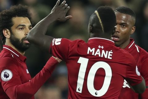 Liverpool's Mohamed Salah, left, Liverpool's Daniel Sturridge, right, and Liverpool's Sadio Mane celebrate after scoring their side's third goal during the English Premier League soccer match between Liverpool and Huddersfield Town at Anfield Stadium, in Liverpool, England, Friday, April 26, 2019.(AP Photo/Jon Super)