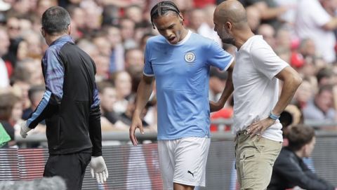 Manchester City's Leroy Sane, left, grimaces walking by Manchester City's manager Pep Guardiola as he leaves the pitch after an injury during the English Community Shield soccer match between Liverpool and Manchester City at Wembley stadium in London, Sunday, Aug. 4, 2019. (AP Photo/Kirsty Wigglesworth)