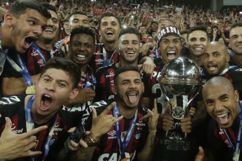 Players of Brazil's Atletico Paranaense celebrate with the trophy after defeating Colombia's Junior 4-3 in a penalty kick shoot-out during the Copa Sudamericana final soccer match at the Arena da Baixada stadium in Curitiba, Brazil, Thursday, Dec. 13, 2018. (AP Photo/Victor Caivano)