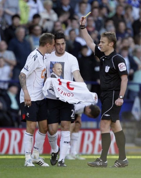 Referee Mike Jones, right, shows a yellow card to Bolton's Tamir Cohen, centre, as the latter replaces his shirt over an undershirt bearing a picture of his late father, the soccer player Avi Cohen, after scoring the winning goal against Arsenal during their English Premier League soccer match at The Reebok Stadium, Bolton, England, Sunday April 24, 2011. (AP Photo/Jon Super) NO INTERNET/MOBILE USAGE WITHOUT FOOTBALL ASSOCIATION PREMIER LEAGUE(FAPL)LICENCE. EMAIL info@football-dataco.com FOR DETAILS.