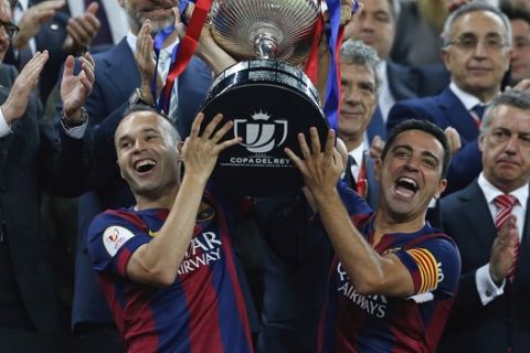 FILE - In this Saturday, May 30, 2015 file photo Barcelona's Andres Iniesta, left, and Xavi Hernandez lift the trophy after winning the final of the Copa del Rey soccer match between FC Barcelona and Athletic Bilbao at the Camp Nou stadium in Barcelona, Spain. (AP Photo/Manu Fernandez, File)