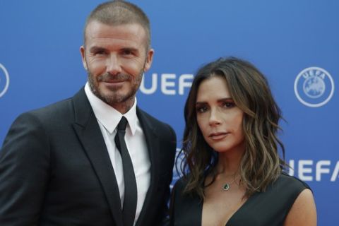 David Beckham, left, and his wife Victoria Beckham arrive for the UEFA Champions League draw at the Grimaldi Forum, in Monaco, Thursday, Aug. 30, 2018. (AP Photo/Claude Paris)