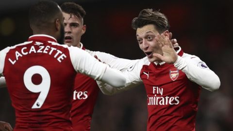 Arsenal's Mesut Ozil, right, celebrates scoring his side's third goal of the game during their English Premier League soccer match between Arsenal and Liverpool at the Emirates stadium London, Friday, Dec. 22, 2017. (John Walton/PA via AP)