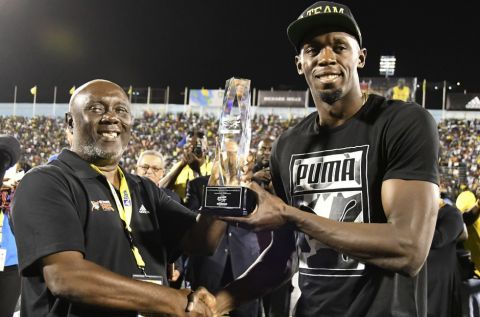 Jamaica's Usain Bolt receives a special award from his coach, Glen Mills, before competing in the "Salute to a Legend" 100 meters during the Racers Grand Prix at the national stadium in Kingston, Jamaica, Saturday, June 10, 2017. Bolt started his final season with his last race on Jamaican soil and plans to retire from track and field after the 2017 London World Championships in August. (AP Photo/Bryan Cummings)