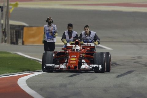 Ferrari driver Sebastian Vettel of Germany has his car pushed back to the pit lane during the second practice session for the Bahrain Formula One Grand Prix, at the Formula One Bahrain International Circuit in Sakhir, Bahrain, Friday, April 14, 2017. The Bahrain Formula One Grand Prix will take place on Sunday. (AP Photo/Luca Bruno)