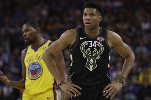 Milwaukee Bucks' Giannis Antetokounmpo (34) stands in front of Golden State Warriors' Kevin Durant during the first half of an NBA basketball game Thursday, March 29, 2018, in Oakland, Calif. (AP Photo/Marcio Jose Sanchez)