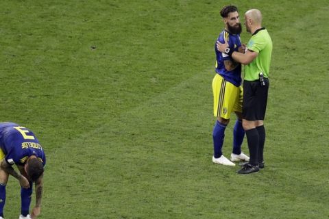 Referee Szymon Marcniak of Poland, right, talks with Sweden's Jimmy Durmaz, middle, at the end the group F match between Germany and Sweden at the 2018 soccer World Cup in the Fisht Stadium in Sochi, Russia, Saturday, June 23, 2018. (AP Photo/Sergei Grits)