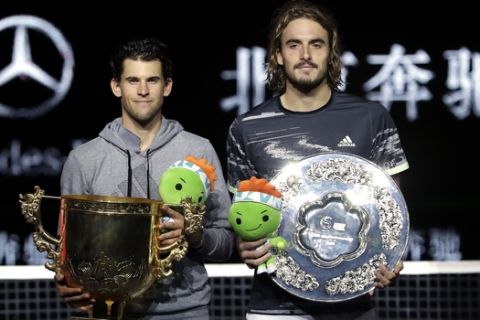 Dominic Thiem of Austria, left, and Stefanos Tsitsipas of Greece hold their trophies after competing in the men's singles championship match at the China Open tennis tournament in Beijing, Sunday, Oct. 6, 2019. (AP Photo/Mark Schiefelbein)