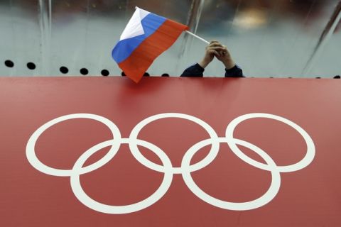 FILE - In this Feb. 18, 2014, file photo, a Russian skating fan holds the country's national flag over the Olympic rings before the start of the men's 10,000-meter speedskating race at Adler Arena Skating Center during the 2014 Winter Olympics in Sochi, Russia. On Monday, July 18, 2016 WADA investigator Richard McLaren confirmed claims of state-run doping in Russia. (AP Photo/David J. Phillip, File)