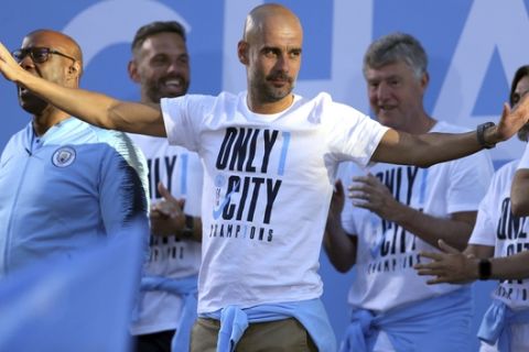 Manchester City soccer team manager Pep Guardiola acknowledges supporters during the British Premier League champions trophy parade in Manchester, England, Monday May 14, 2018.  Manchester City soccer team paraded through the streets of Manchester aboard open top buses, celebrating winning the Premier League title by a record 19 points. (Richard Sellers/PA via AP)