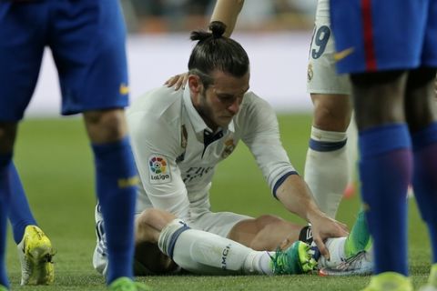 Real Madrid's Gareth Bale holds his leg after getting injured during a Spanish La Liga soccer match between Real Madrid and Barcelona, dubbed 'el clasico', at the Santiago Bernabeu stadium in Madrid, Spain, Sunday, April 23, 2017. (AP Photo/Daniel Ochoa de Olza)
