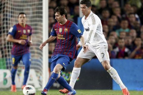 Barcelona's Lionel Messi (L) passes the ball beside Real Madrid's Cristiano Ronaldo during their Spanish first division "El Clasico" soccer match at Nou Camp stadium in Barcelona April 21, 2012.      REUTERS/Juan Medina (SPAIN  - Tags: SPORT SOCCER)  
