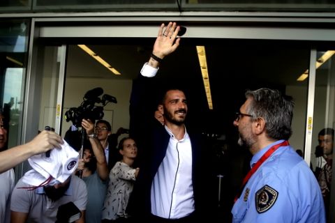 Italy defender Leonardo Bonucci waves to fans as he walks off AC Milan's headquarters, in Milan, Italy, Friday, July 14, 2017. Bonucci is close to completing a transfer from Juventus to rival AC Milan that could signal a shift in the balance of power in Serie A. (AP Photo/Luca Bruno)