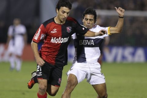 Ignacio Scocco of Argentina's Newell's Old Boys, left, vies for the ball with Walter Erviti of Argentina's Boca Juniors, during a Copa Libertadores soccer match in Rosario, Argentina, Wednesday, May 29, 2013. (AP Photo/Daniel Jayo)
