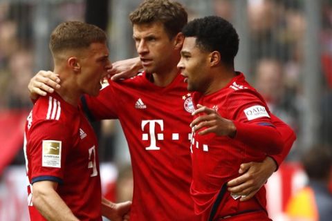 Bayern's Serge Gnabry, right, celebrates with team mates Thomas Mueller, center, and Joshua Kimmich after scoring his side's opening goal during the German Bundesliga soccer match between FC Bayern Munich and VfL Wolfsburg in Munich, Germany, Saturday, March 9, 2019. (AP Photo/Matthias Schrader)