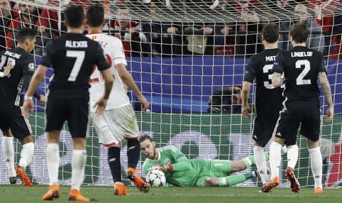 Manchester United goalkeeper David de Gea, center, dives for a save during the Champions League round of sixteen first leg soccer match between Sevilla FC and Manchester United at the Ramon Sanchez Pizjuan stadium in Seville, Spain, Wednesday, Feb. 21, 2018. (AP Photo/Miguel Morenatti)