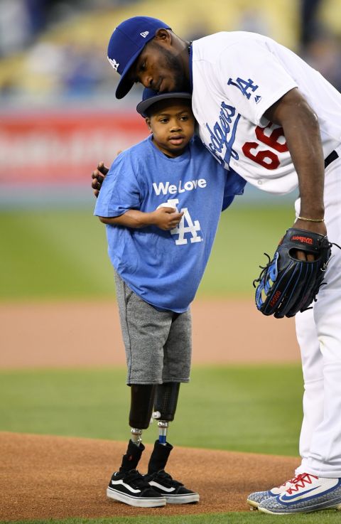 Zion Harvey, 10, gets a hug from Los Angeles Dodgers' Yasiel Puig after throwing out the ceremonial first pitch at a game between the Dodgers and the Arizona Diamondbacks, Friday, April 14, 2017, in Los Angeles. Harvey lost parts of his legs to a sepsis infection. (AP Photo/Mark J. Terrill)