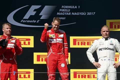 Ferrari driver Sebastian Vettel of Germany celebrates after winning the Hungarian Formula One Grand Prix, at the Hungaroring racetrack in Mogyorod, northeast of Budapest, Sunday, July 30, 2017. At left is second placed Ferrari driver Kimi Raikkonen of Finland and at right third placed Mercedes driver Valtteri Bottas of Finland. (AP Photo/Darko Bandic)