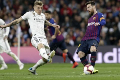 Barcelona forward Lionel Messi, right, passes the ball as Real midfielder Toni Kroos defends during the Spanish La Liga soccer match between Real Madrid and FC Barcelona at the Bernabeu stadium in Madrid, Saturday, March 2, 2019. (AP Photo/Andrea Comas)