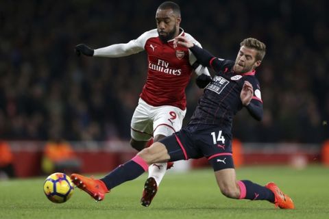 Arsenal's Alexandre Lacazette, left, and Huddersfield Town's Martin Cranie battle for the ball during the English Premier League match at the Emirates Stadium, London, Wednesday Nov. 29, 2017. (Nigel French/PA via AP)