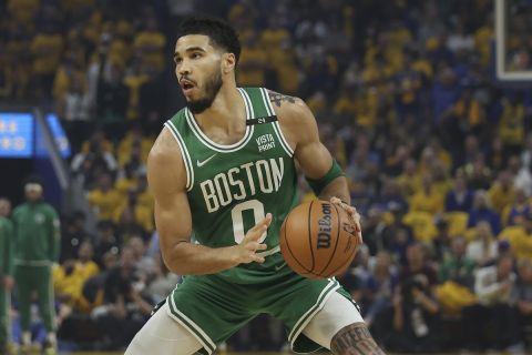 Boston Celtics forward Jayson Tatum (0) is defended by Golden State Warriors center Kevon Looney during the first half of Game 1 of basketball's NBA Finals in San Francisco, Thursday, June 2, 2022. (AP Photo/Jed Jacobsohn)