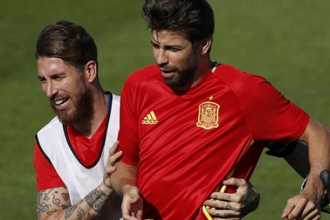 FILE - In this June 24, 2016 file photo, Spain's Sergio Ramos, left, grabs Gerard Pique during a training session at the Sports Complex Marcel Gaillard in Saint Martin de Re in France. Sergio Ramos and Gerard Pique, defenders from rival clubs Real Madrid and Barcelona are calling a truce and are at peace while with Spain's national team after exchanging blows through social media and television interviews recently. (AP Photo/Manu Fernandez, File)