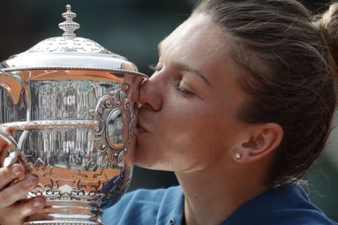 Romania's Simona Halep kisses the trophy as she celebrates winning the final match of the French Open tennis tournament against Sloane Stephens of the U.S. in three sets 3-6, 6-4, 6-1, at the Roland Garros stadium in Paris, France, Saturday, June 9, 2018. (AP Photo/Alessandra Tarantino)