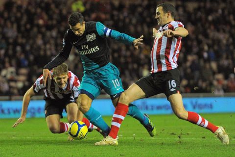 Arsenal's Dutch striker Robin van Persie (2nd L) vies with Sunderland's English defender Michael Turner (L) and Irish defender John O'Shea (R) during the English 5th Round FA Cup football match between Sunderland and Arsenal at The Stadium Of Light, in Sunderland, north-east England, on February 18 2012. AFP PHOTO/ANDREW YATES  

RESTRICTED TO EDITORIAL USE. No use with unauthorized audio, video, data, fixture lists, club/league logos or live services. Online in-match use limited to 45 images, no video emulation. No use in betting, games or single club/league/player publications. (Photo credit should read ANDREW YATES/AFP/Getty Images)