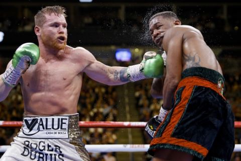 Canelo Alvarez, left, of Mexico, hits Daniel Jacobs during a middleweight title boxing match Saturday, May 4, 2019, in Las Vegas. (AP Photo/John Locher)
