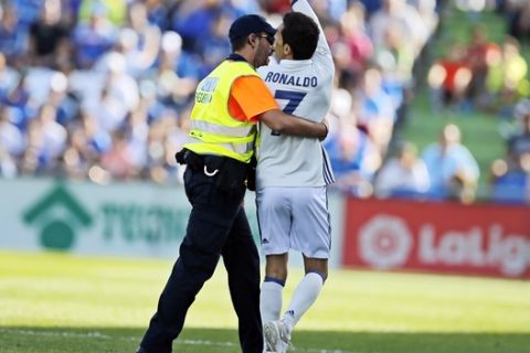 A security guard grabs a fan wearing a Cristiano Ronaldo shirt after he invaded the pitch during a Spanish La Liga soccer match between Getafe and Real Madrid at the Coliseum Alfonso Perez in Getafe, Spain, Saturday, Oct. 14, 2017. (AP Photo/Paul White)
