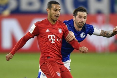 Bayern's Thiago, left, and Schalke's Guido Burgstaller challenge for the ball during the German soccer cup, DFB Pokal, quarter-final match between FC Schalke 04 and Bayern Munich in Gelsenkirchen, Germany, Tuesday, March 3, 2020. (AP Photo/Martin Meissner)