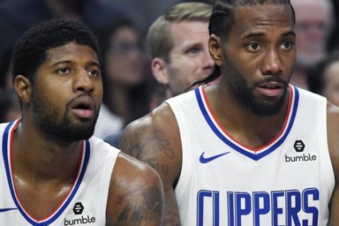 Los Angeles Clippers forward Paul George, left, and forward Kawhi Leonard sit on the bench during the second half of the team's NBA basketball game against the Boston Celtics on Wednesday, Nov. 20, 2019, in Los Angeles. (AP Photo/Mark J. Terrill)
