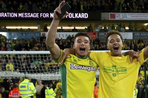 Norwich City's Ben Godfrey, left, and Norwich City's Jamal Lewis celebrate promotion to the Premier League after the English Championship soccer match against Blackburn Rovers at Carrow Road, Norwich, England, Saturday April 27, 2019. Norwich is returning to the Premier League after a three-year absence _ and Sheffield United is likely to be promoted, too. Norwich, a club from eastern England, clinched one of the two automatic promotion places from the second-tier League Championship by beating Blackburn 2-1 on Saturday.(Chris Radburn/PA via AP)