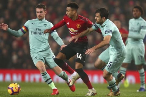 Manchester United's midfielder Jesse Lingard, center, Arsenal's Aaron Ramsey, left, and Arsenal's Sokratis Papastathopoulos, right, vie for the ball during the English Premier League soccer match between Manchester United and Arsenal at Old Trafford stadium in Manchester, England, Wednesday Dec. 5, 2018. (AP Photo/Dave Thompson)