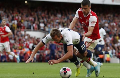Tottenham's Harry Kane, left, fights for the ball with Arsenal's Sokratis Papastathopoulos during their English Premier League soccer match between Arsenal and Tottenham Hotspur at the Emirates stadium in London, Sunday, Sept. 1, 2019. (AP Photo/Alastair Grant)