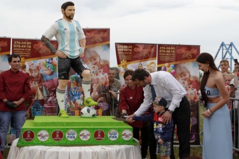 The major of Bronnitsy helps a boy cut a cake to mark Lionel Messi's birthday near Argentina training camp base at the 2018 World Cup in Bronnitsy, Russia, Sunday, June 24, 2018. Wth a cake sculpture and a music festival the town of Bronnitsy celebrated the striker's 31st birthday.(AP Photo/Ricardo Mazalan)