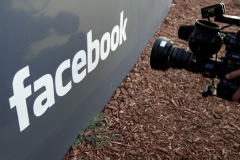 FILE- In this May 18, 2012, file photo a television photographer shoots the sign outside of Facebook headquarters in Menlo Park, Calif. S&P Dow Jones Indices is shuffling the line-up of three of the 11 groups that make up the benchmark S&P 500 index. On Monday, 20 companies in the index including famous names like Facebook, Alphabet and Netflix will find a new home. (AP Photo/Paul Sakuma, File)