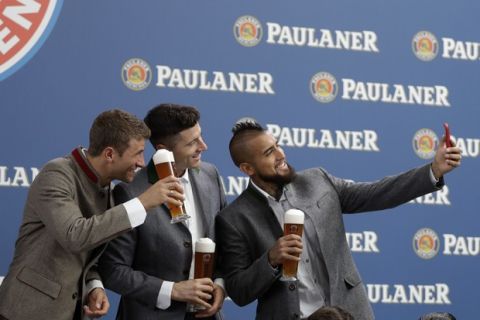 Bayern's Thomas Mueller, from left, Robert Lewandowski and Arturo Vidal make selfies in traditional Bavarian clothes during a photo shooting of a beer brewing company in Munich, Germany, Wednesday, Sept. 13, 2017. (AP Photo/Matthias Schrader)