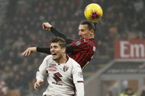 AC Milan's Zlatan Ibrahimovic, top, jumps for the ball with Torino's Lyanco during the Serie A soccer match between AC Milan and Torino at the San Siro stadium, in Milan, Italy, Monday, Feb. 17, 2020. (AP Photo/Antonio Calanni)