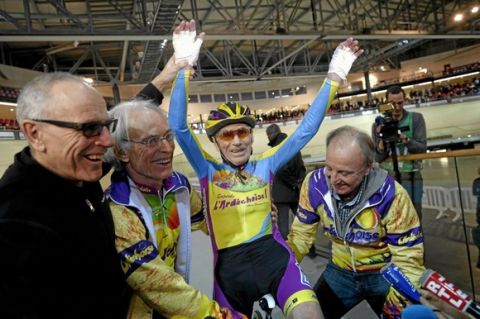 Robert Marchand (C), who is 102 years old, celebrates with friends after beating his own hourly cycling record, on January 31, 2014, at the national Velodrome of Saint-Quentin-en-Yvelines in Montigny-le-Bretoneux. AFP PHOTO / LIONEL BONAVENTURE