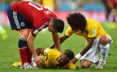 FORTALEZA, BRAZIL - JULY 04: Neymar of Brazil lies on the field after a challenge as teammate Marcelo and James Rodriguez of Colombia look on during the 2014 FIFA World Cup Brazil Quarter Final match between Brazil and Colombia at Castelao on July 4, 2014 in Fortaleza, Brazil.  (Photo by Jamie McDonald/Getty Images)